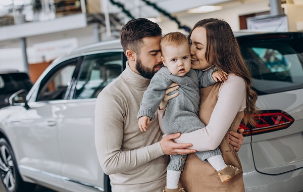 Family with baby girl choosing a car in a car salon